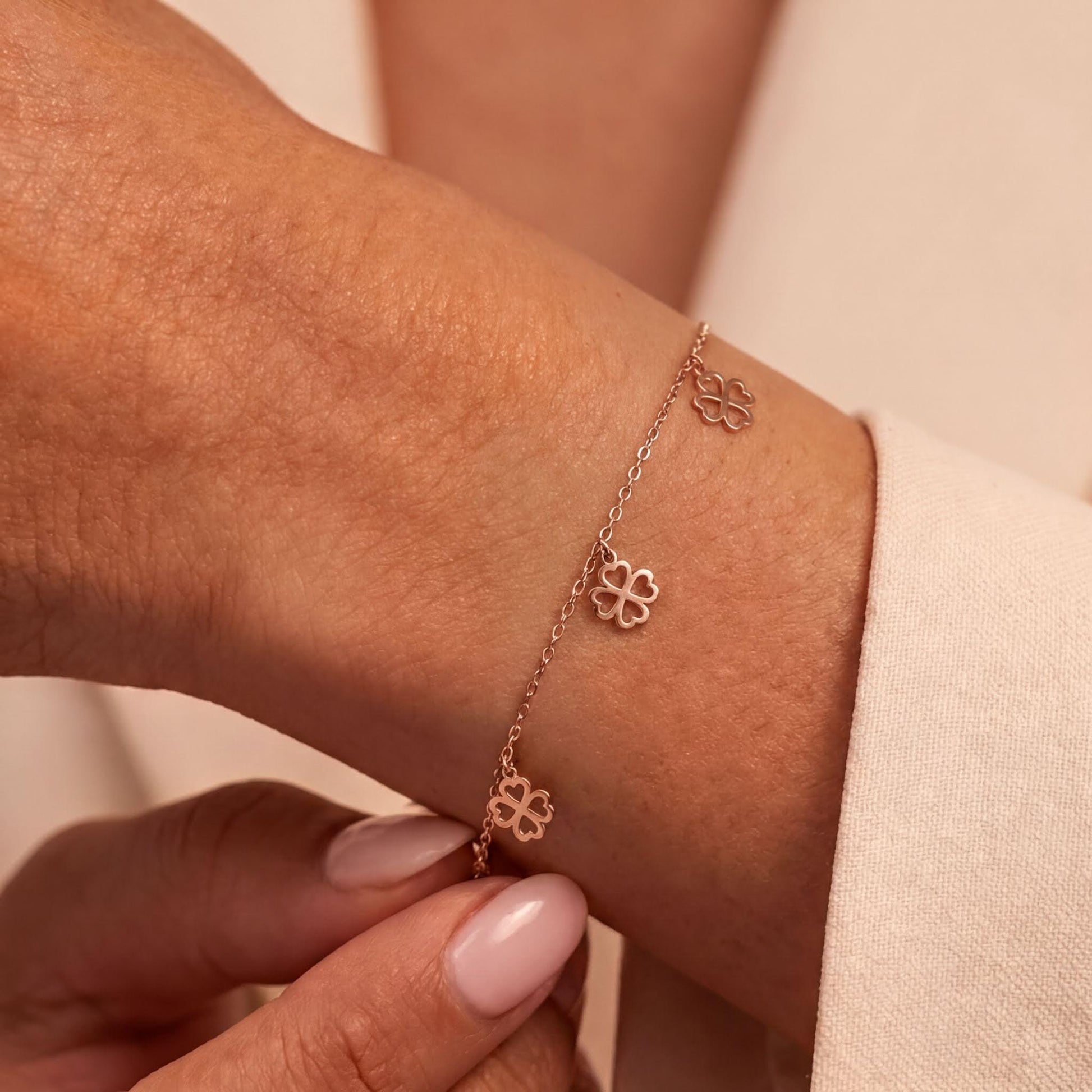 A close-up view of a person's wrist wearing a delicate gold-colored bracelet with small flower-shaped charms.