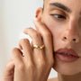 A close-up of a woman's face, focusing on her hand and ring.