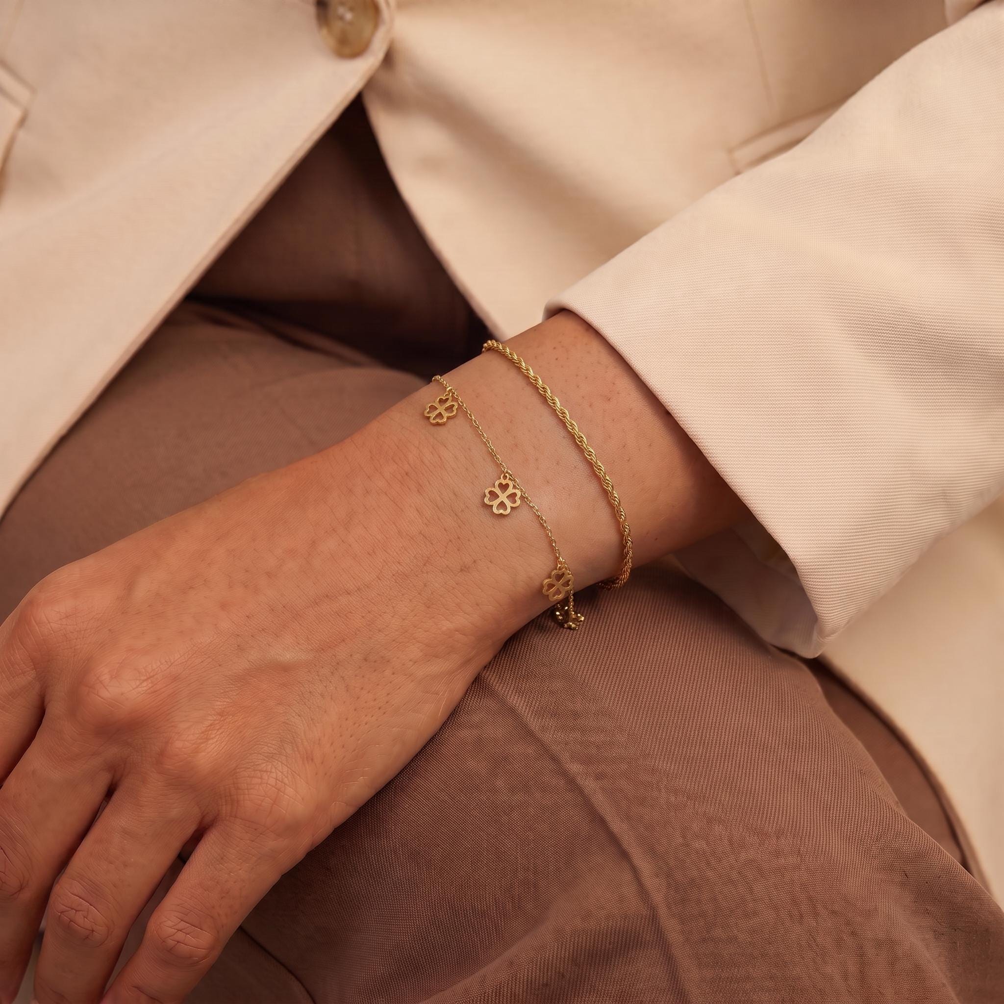A close-up view of a person's wrist wearing a gold-colored bracelet with charms on it.