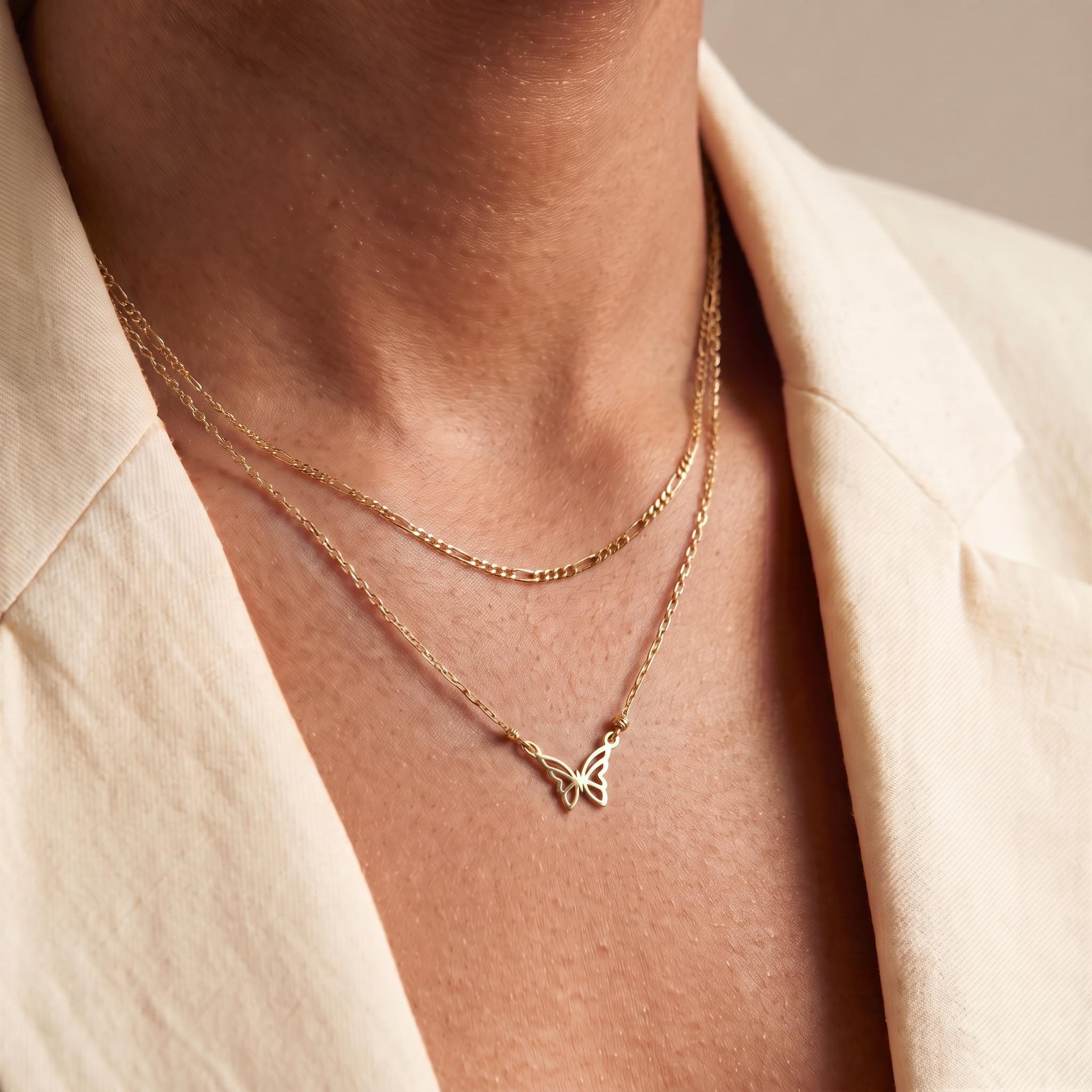 A close-up view of a person's neck and chest area, showing a delicate gold necklace with a butterfly pendant.