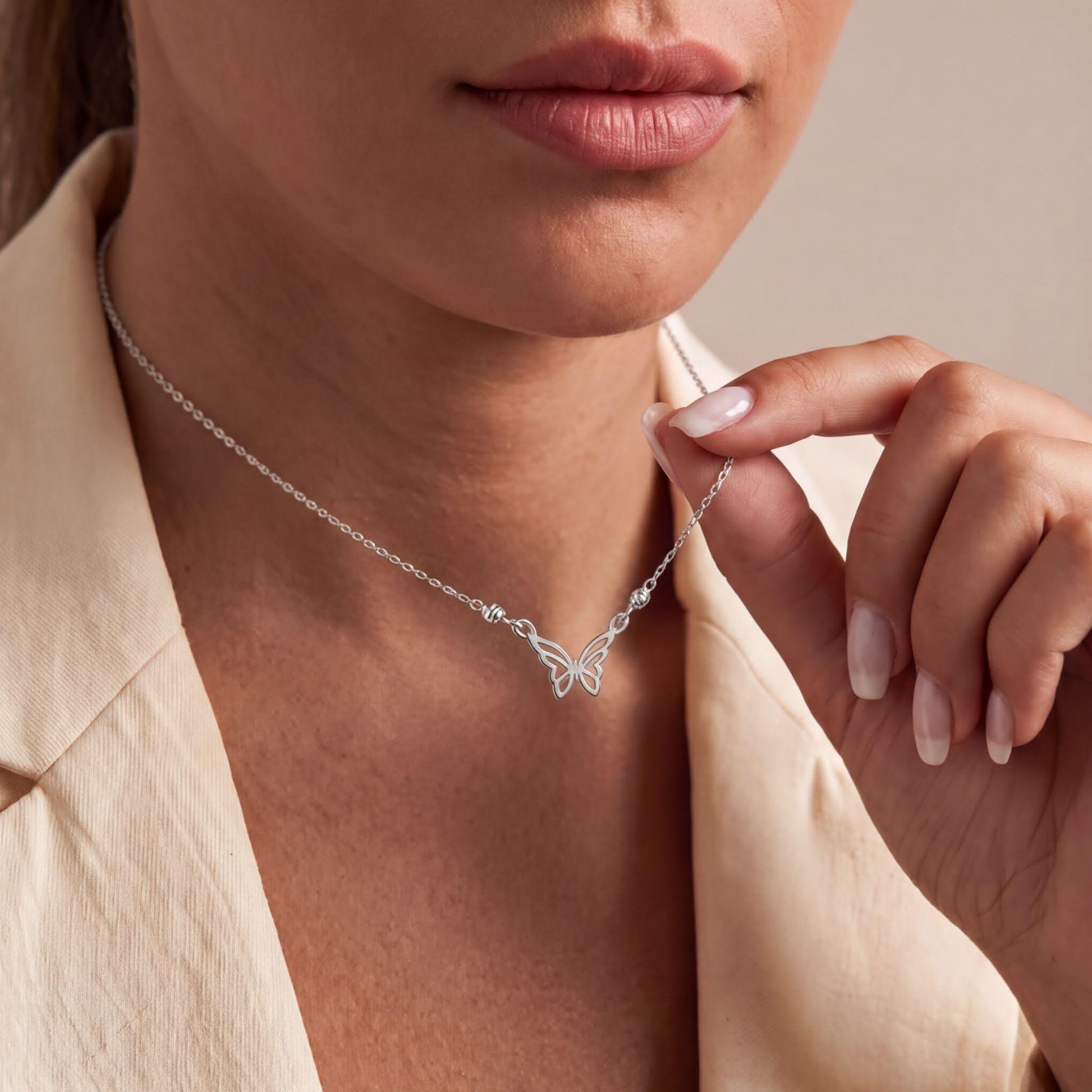 A close-up of a woman's neck and chin wearing a silver necklace with a butterfly design.